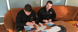 Dwaj strażacy z JRG Słupca przygotowują ulotki informacyjne dot. szczepień na COVID-19