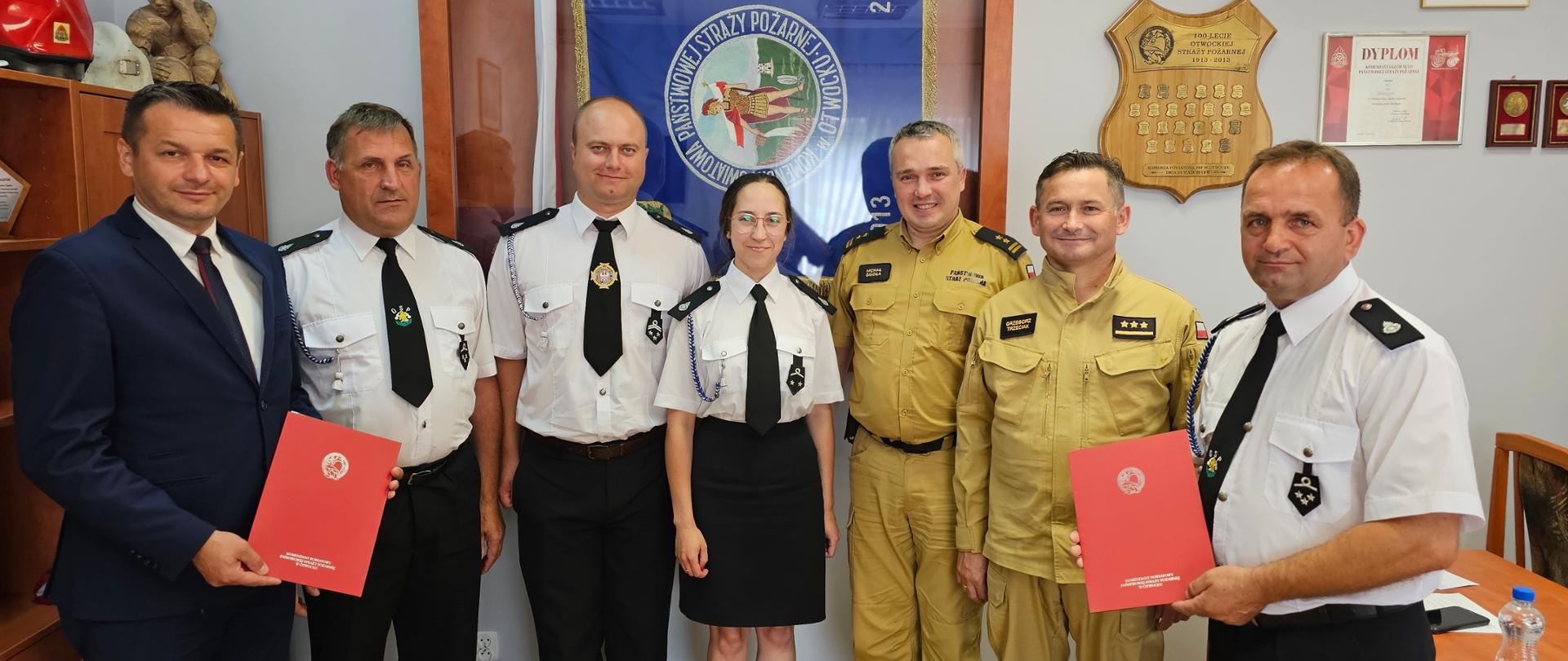 W gabinecie Komendanta Powiatowego PSP w Otwocku stoją od lewej strony: Wójt Gminy Sobienie Jeziory Pan Kamil Choim, następnie troje druhów OSP Dziecinów, Komendant Powiatowy bryg. Michał Gigoła, Zastęca Komendanta Powiatowego kpt. Grzegorz Trzeciak oraz Prezes OSP Dziecinów Krzysztof Grzegrzółka 