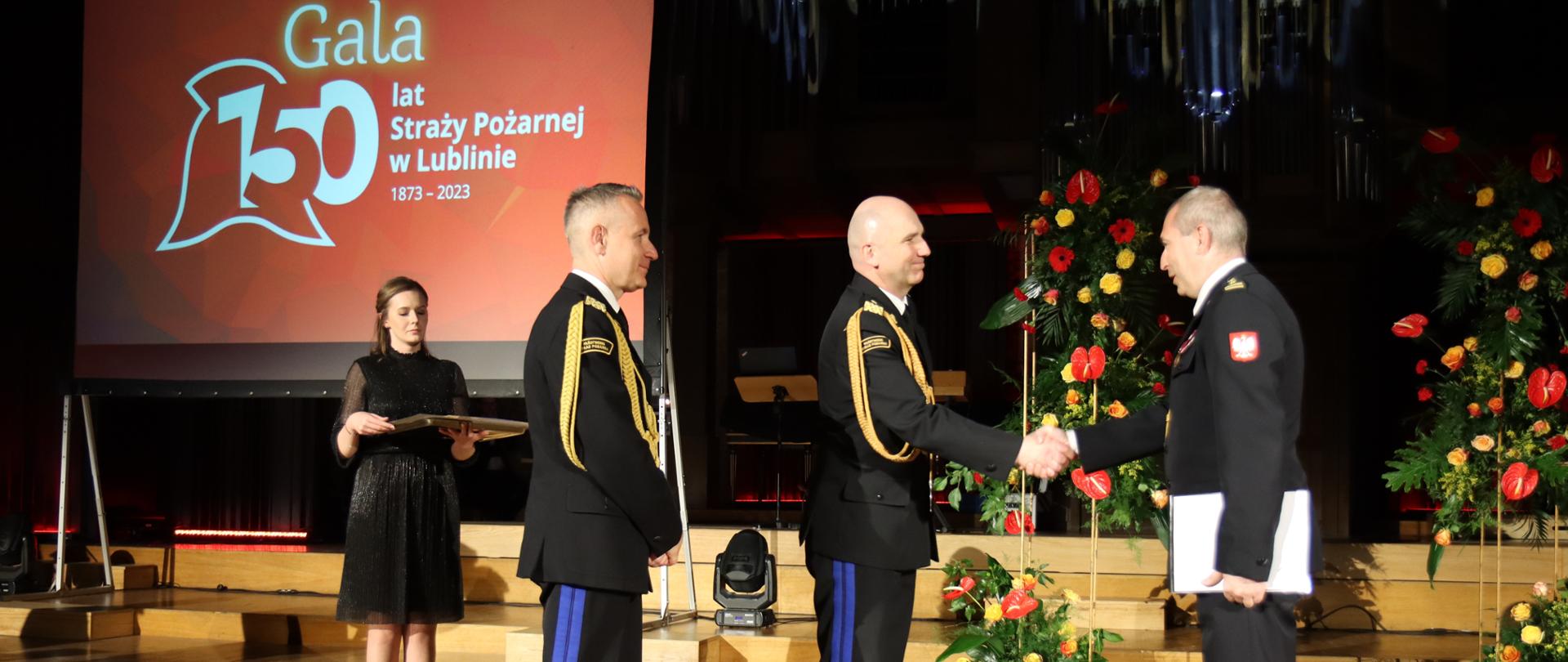 Komendant główny PSP wraz z komendantem wojewódzkim wręczają dyplom strażakowi PSP