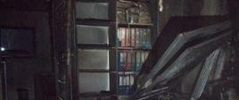 Wnętrze pomieszczenia biurowego po pożarze. Wszystkie elementy wyposażenia okopcone i częściowo nadpalone.