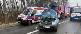 Na zdjęciu znajduje się wrak samochodu osobowego, w tle widać karetki pogotowia i straż