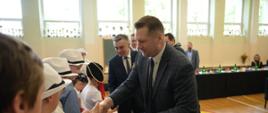 Minister Czarnek ściska dłoń małemu dziecku.