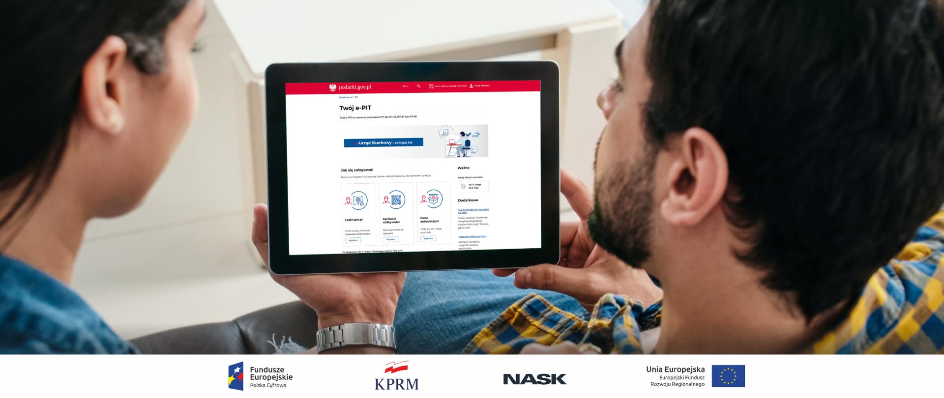 Dwie osoby, trzymają w rękach komputer. Na komputerze wyświetla się strona podatki.gov.pl. Próbują się zalogować do Urzędu Skarbowego w celu rozliczenia swojego PIT. 
