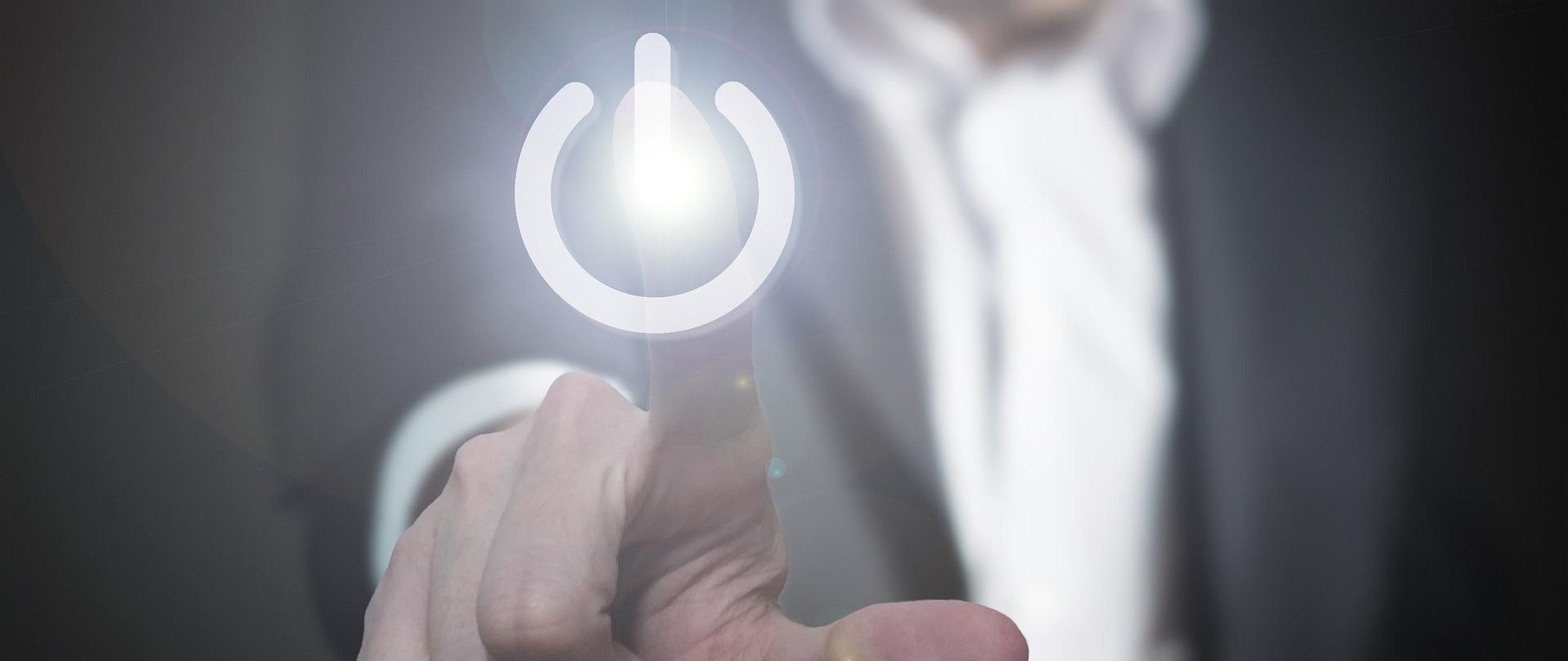 dłoń przyciskająca ikonę włącznika