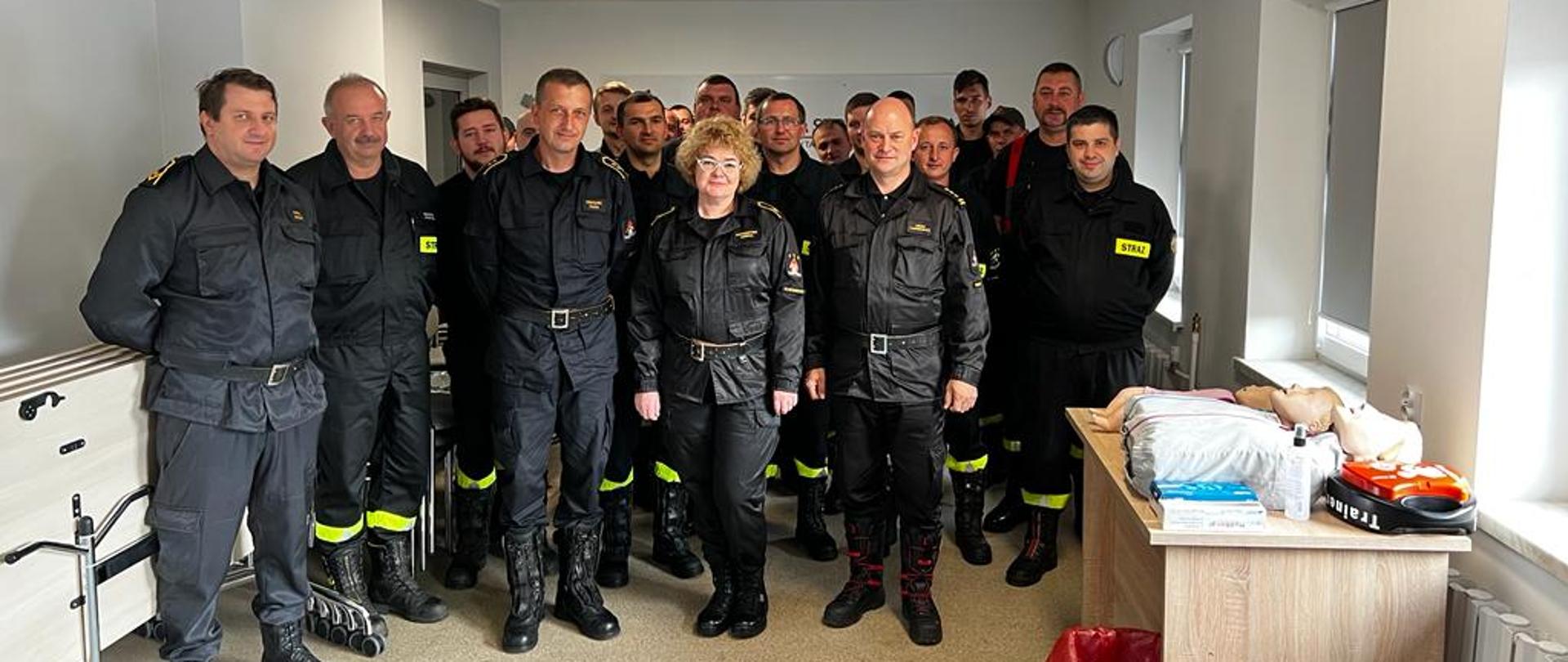 Strażacy w czarnych mundurach pozują do zdjęcia