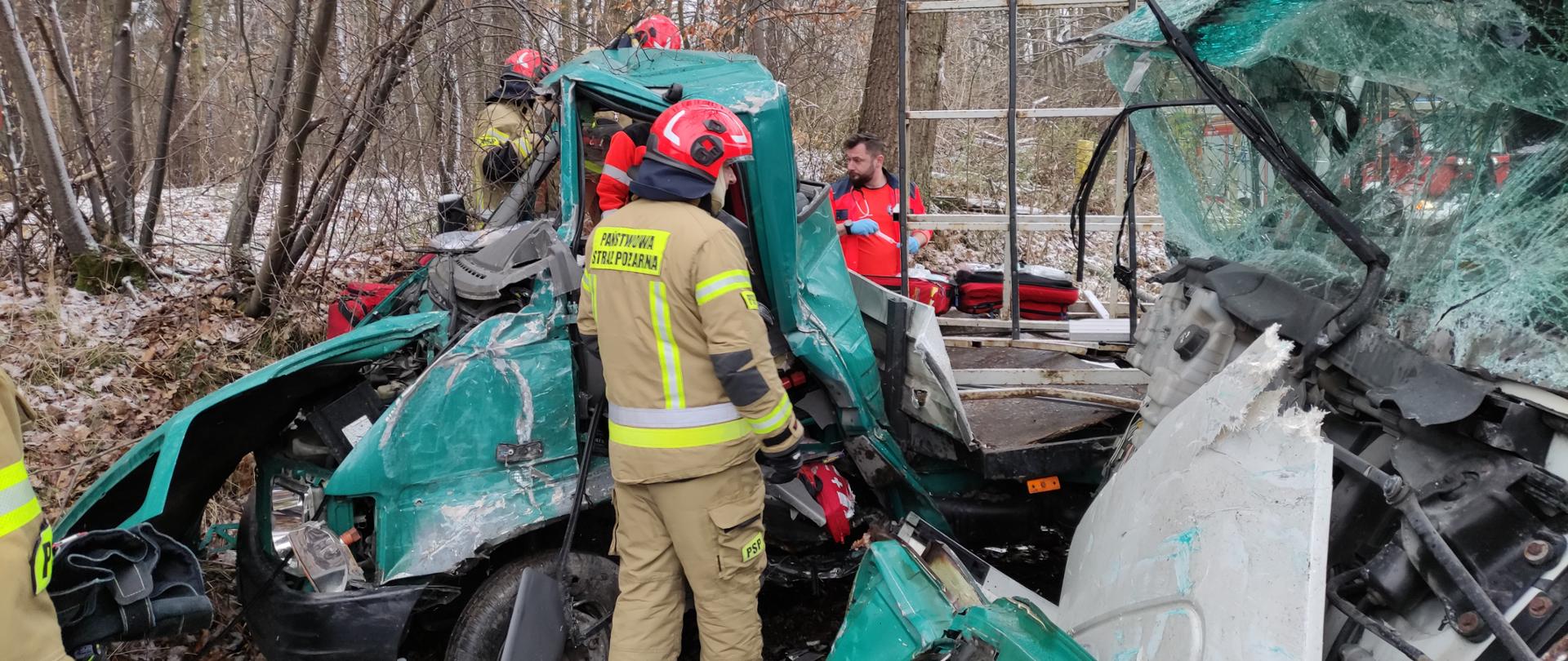 Strażacy pomagają w przemieszczeniu osoby poszkodowanej z uszkodzonego pojazdu do karetki