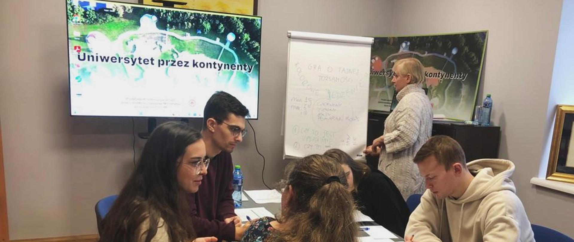 Młodzi ludzie siedzą przy stole i pracują