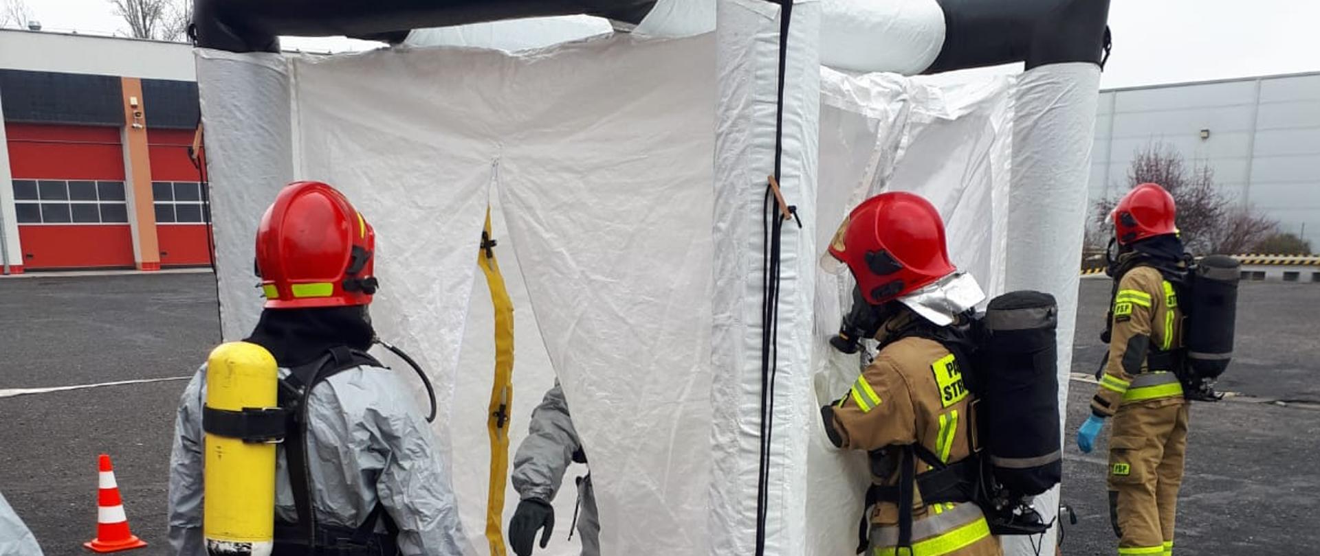 Strażacy w oporządzeniu działają z zagrożeniem chemicznym.
