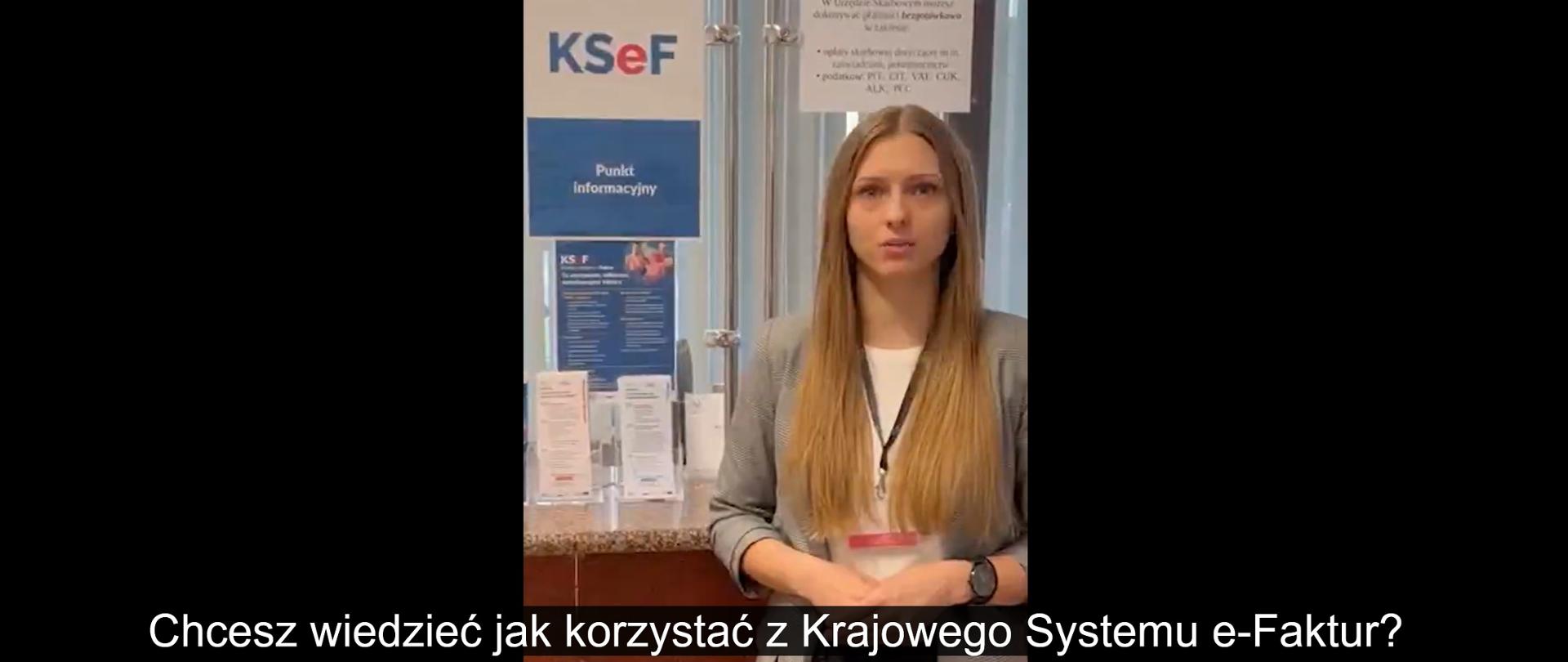 Sala obsługi. Pracownica Urzędu Skarbowego w Strzyżowie. Obok wisi plakat KSeF. 