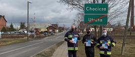 Zdjęcie przedstawiające Strażaków OSP prezentujących ulotki roznoszone w ramach akcji informacyjnej #SZCZEPIMY SIĘ