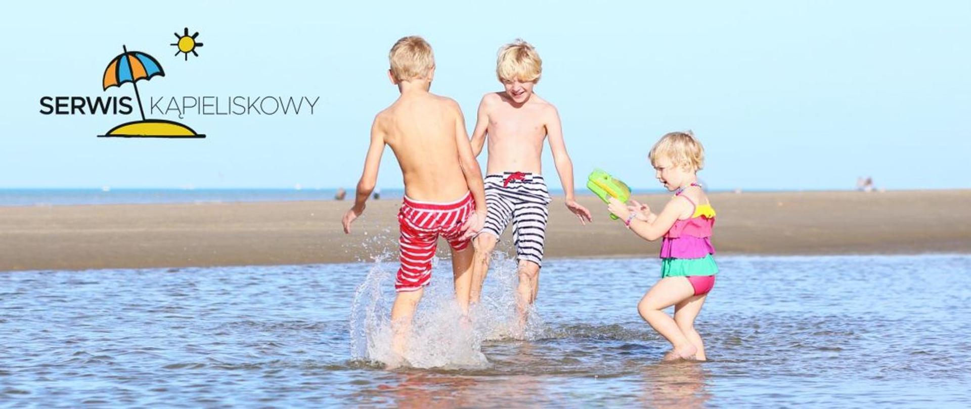 Zdjęcie dzieci bawiących się w wodzie przy plaży. Logo Serwisu Kąpieliskowego.