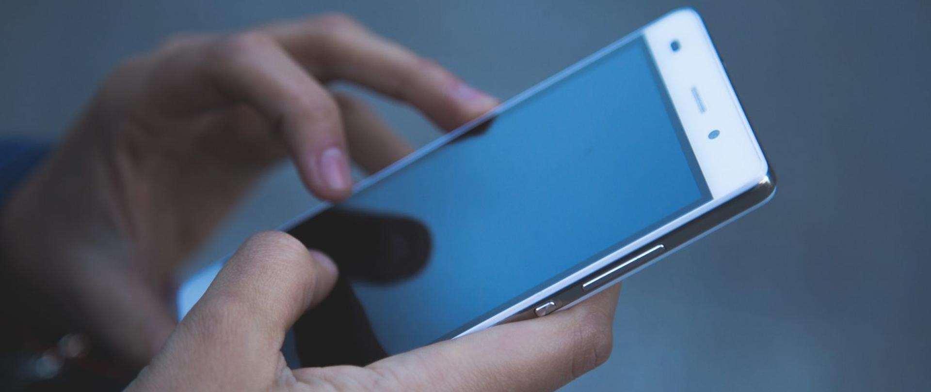 dłonie trzymające telefon komórkowy