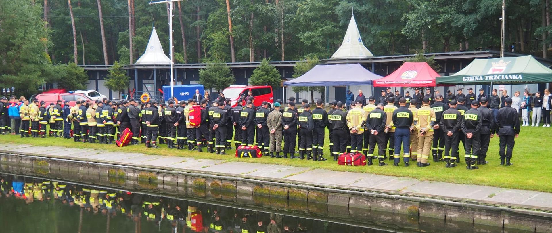 Strażacy w dwuszeregu. Przed nimi organizatorzy