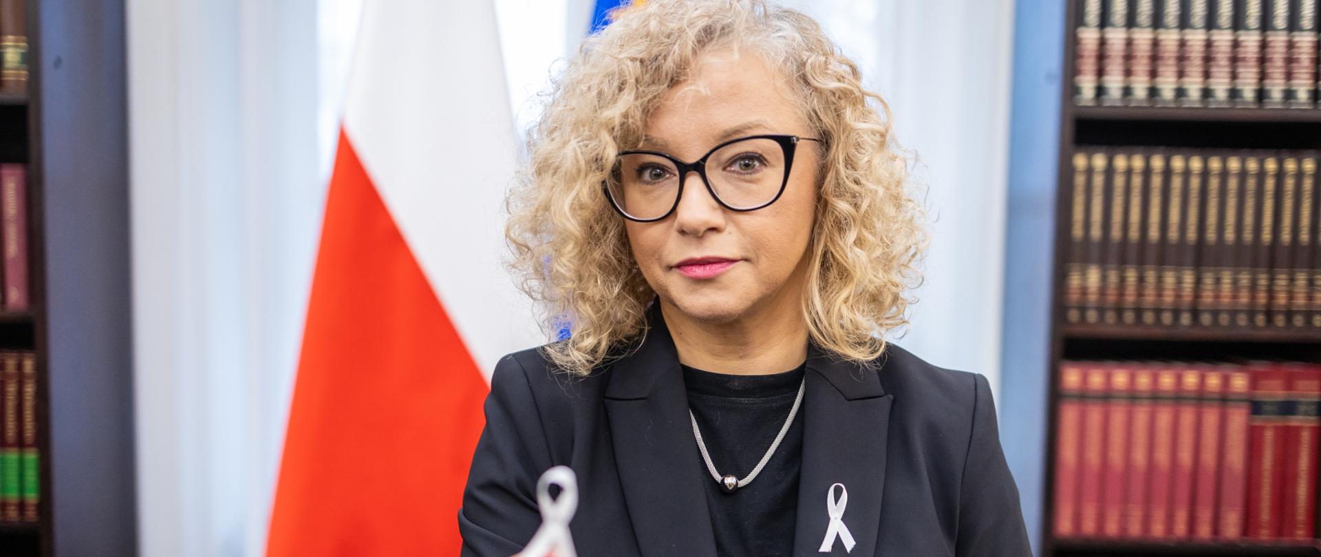 Sekretarz Stanu w KPRM Katarzyna Kotula trzymająca w dłoni białą wstążkę - symbol Dnia Eliminacji Przemocy Wobec Kobiet