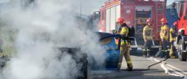 Strażacy gaszą pożar samochodu osobowego.