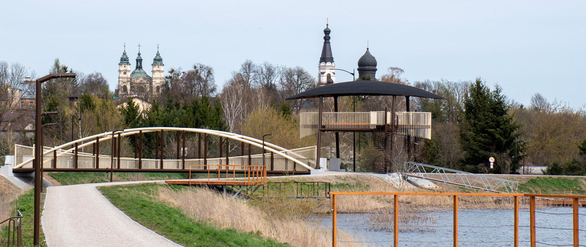 Most pieszo-rowerowy nad zbiornikiem retencyjnym wraz z pomostami, punktem widokowym i infrastrukturą rekreacyjną.