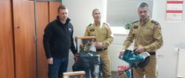 Na zdjęciu widać strażaków dziękujących za zakupienie sprzętu do tutejszej komendy.