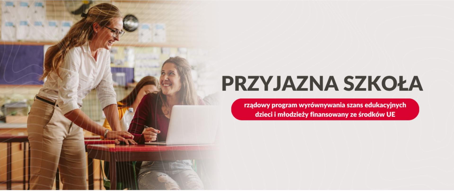 Baner promujący program „PRZYJAZNA SZKOŁA”, będący rządowym programem wyrównywania szans edukacyjnych dzieci i młodzieży finansowanym ze środków Unii Europejskiej. Po lewej stronie grafiki widoczne jest zdjęcie przedstawiające uśmiechniętą nauczycielkę w okularach, która pochyla się nad uczennicą siedzącą przy laptopie w sali lekcyjnej. W dolnej części baneru znajdują się logotypy i flagi potwierdzające finansowanie: „Fundusze Europejskie dla Rozwoju Społecznego”, flaga Polski z napisem „Rzeczpospolita Polska” oraz flaga Unii Europejskiej z tekstem „Dofinansowane przez Unię Europejską”.