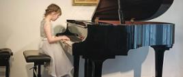 Zdjęcie przedstawia uczennicę podczas gry na fortepianie