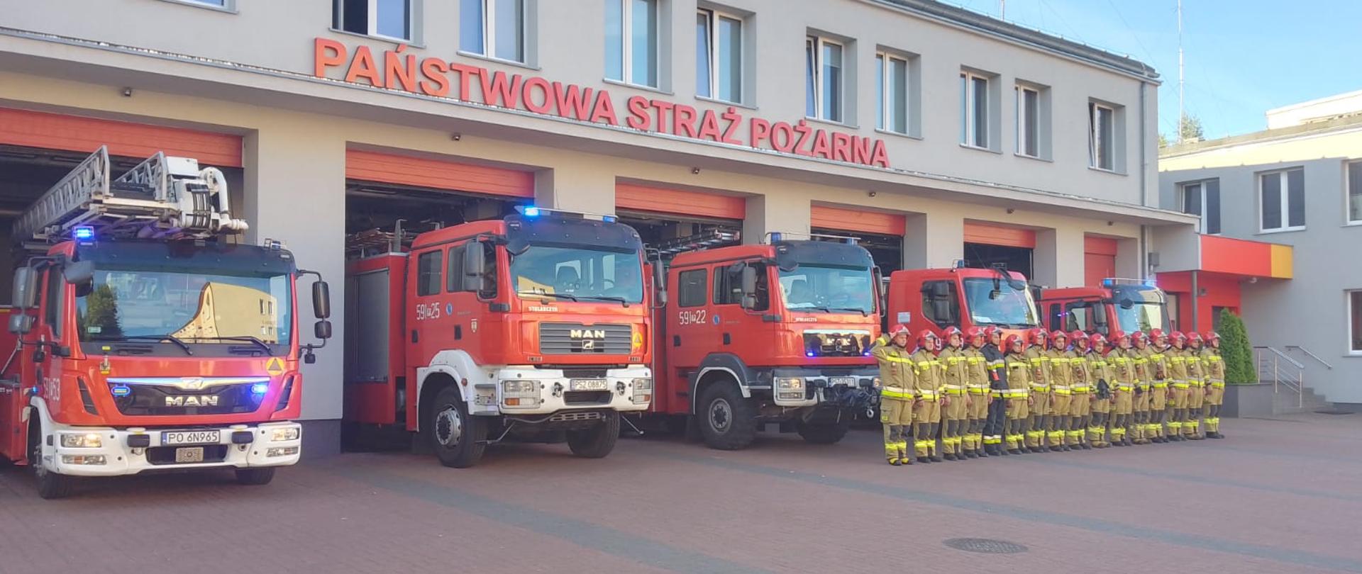 Widać strażaków na tle komendy i samochodów, oddają hołd zmarłemu koledze
