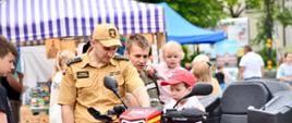 Strażak pokazuje dzieciom quad wykorzystywany w działaniach ratowniczych.