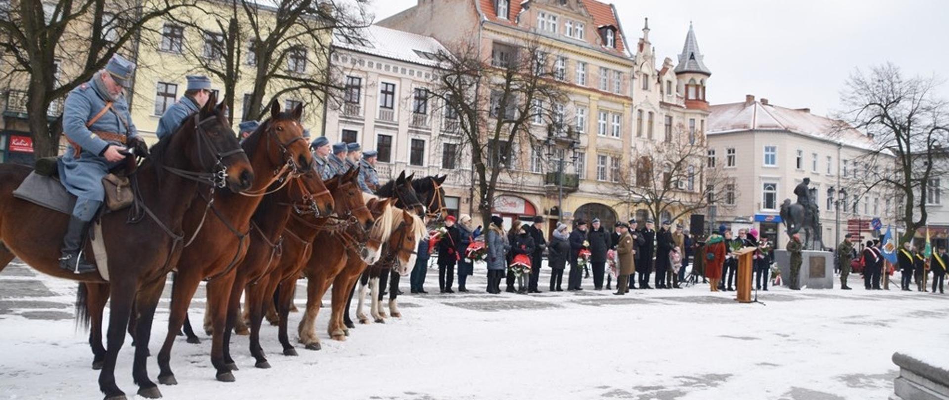 Na zdjęciu znajdują się delegacje służb mundurowych oraz przedstawiciele instytucji miejskich i samorządowych, przy pomniku 8. Pułku Strzelców Konnych na chełmińskim rynku.