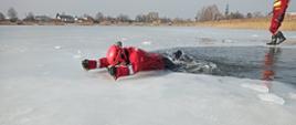 Na zdjęciu widać funkcjonariusza Państwowej Straży Pożarnej który przy pomocy kolców lodowych wydostaje się z wody (symulacja wyjścia z wody po zarwaniu lodu)