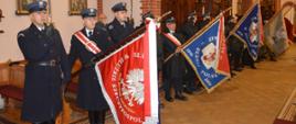 Narodowe Święto Niepodległości. Zdjęcie przedstawia wnętrze kościoła farnego w Rawiczu. W nawie bocznej, na tle ściany i konfesjonału stoją poczty sztandarowe. Pierwszy to poczet wystawiony przez Służbę Więzienną ZK w Rawiczu, pozostałe to poczty strażackie. Sztandarowi pochylają sztandary, a pozostali członkowie pocztu - salutują.