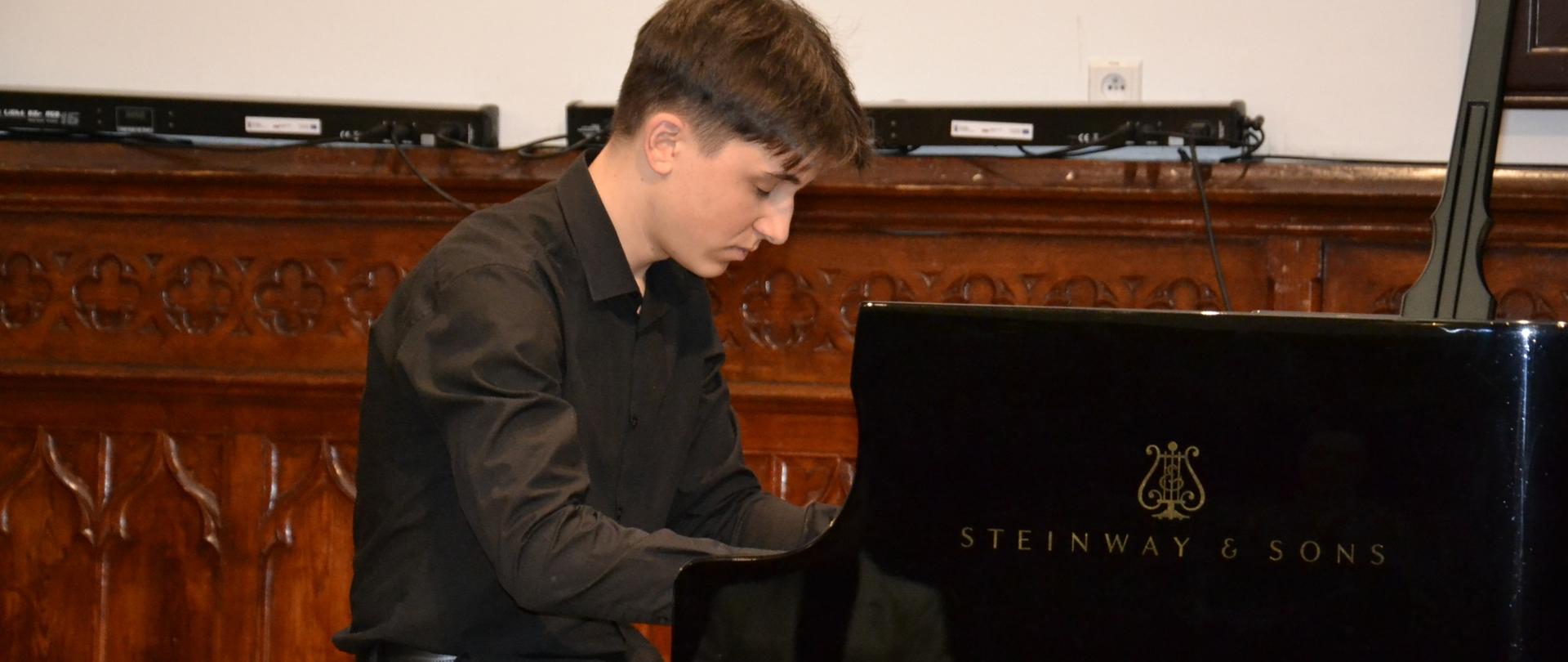 Juliusz Łukasik grający na fortepianie marki Steinway w Sali Królewskiej podczas recitalu fortepianowego