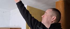 Strażak montuje czujnik dymu na suficie.