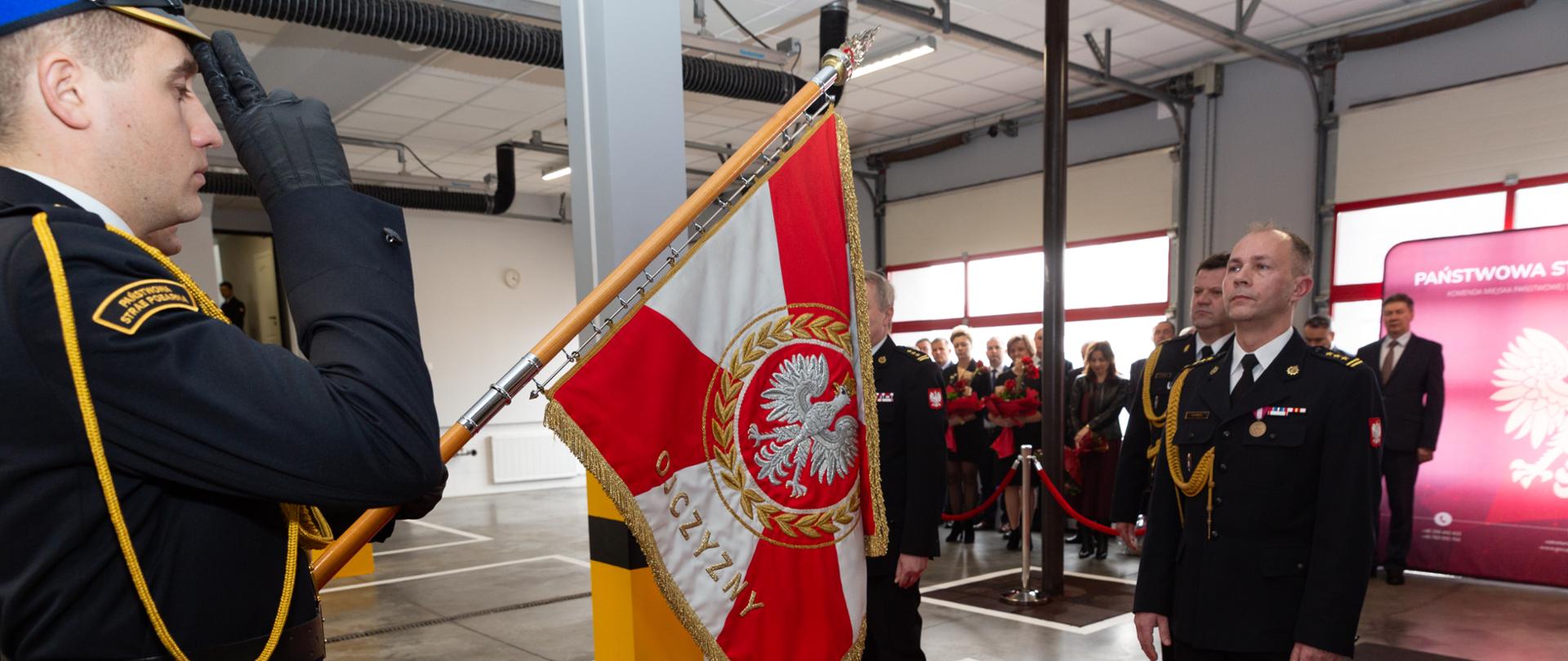 Po lewej stronie zdjęcia poczet sztandarowy z opuszczonym sztandarem, z prawej strażacy w mundurach galowych