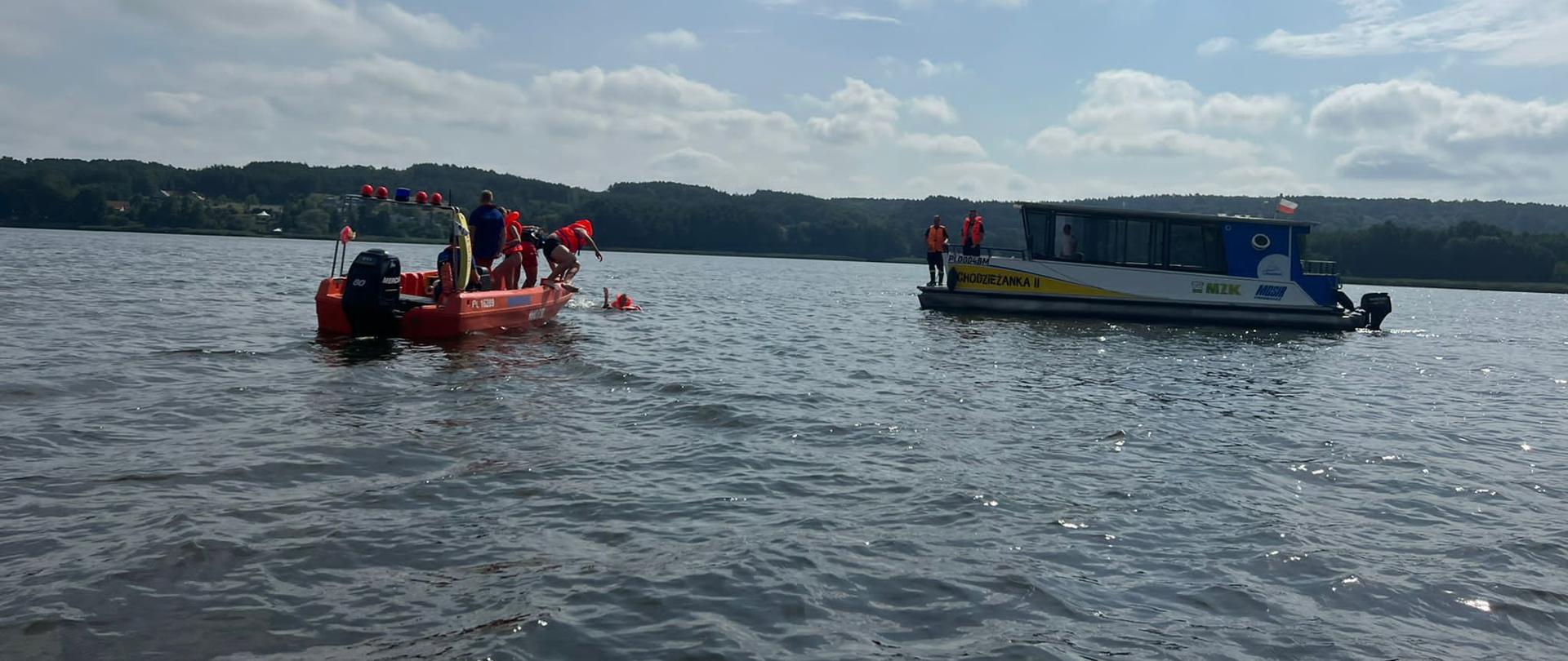 na zdjęciu statek spacerowy Chodzieżanka II, dwie osoby w wodzie podejmowane przez ratowników WOPR na łódź ratowniczą, w tle Jezioro Miejskie
