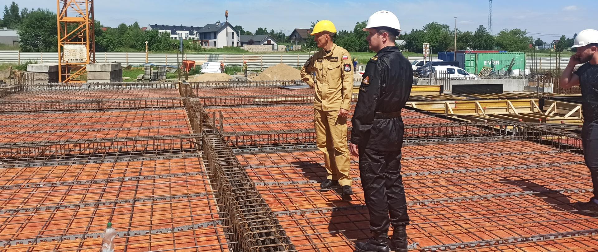 Na zdjęciu zastępca małopolskiego komendanta wojewódzkiego PSP mł. bryg. Przemysław Przęczek oraz komendant powiatowy PSP w Wieliczce mł. bryg. Leszek Kasiński wizytujący plac budowy Komendy Powiatowej PSP w Wieliczce. Funkcjonariusze w umundurowaniu sztabowym na płycie budowy.