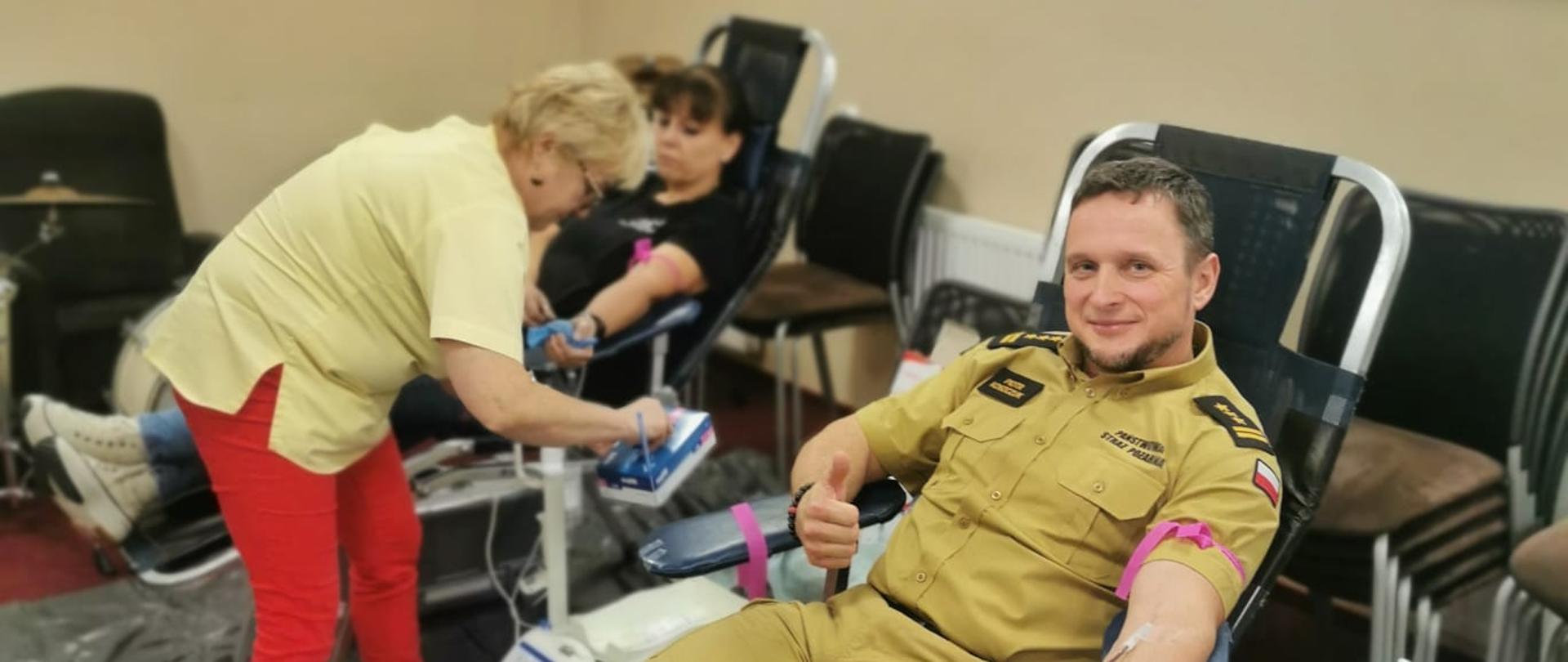 Na leżaku leży strażak i oddaje krew.