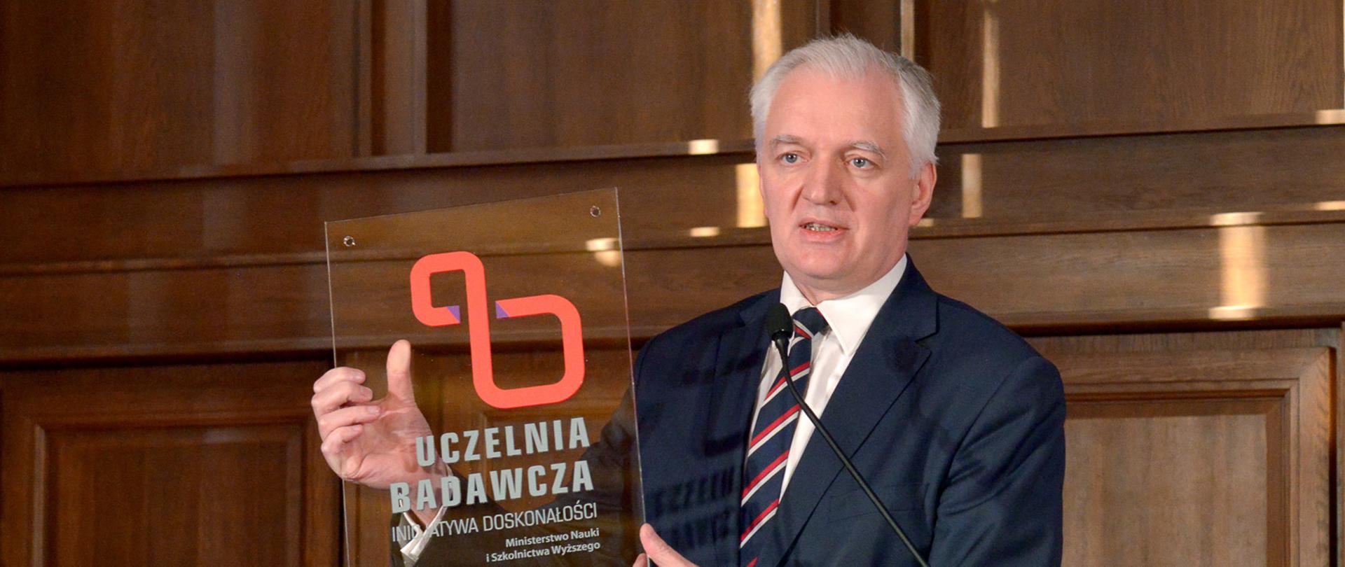 Przy mównicy wicepremier Jarosław Gowin ze statuetką konkursu IDUB