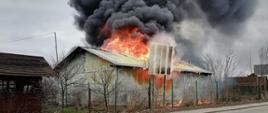 Zdjęcie przedstawia budynek warsztatowy, z którego wychodzą płomienie.