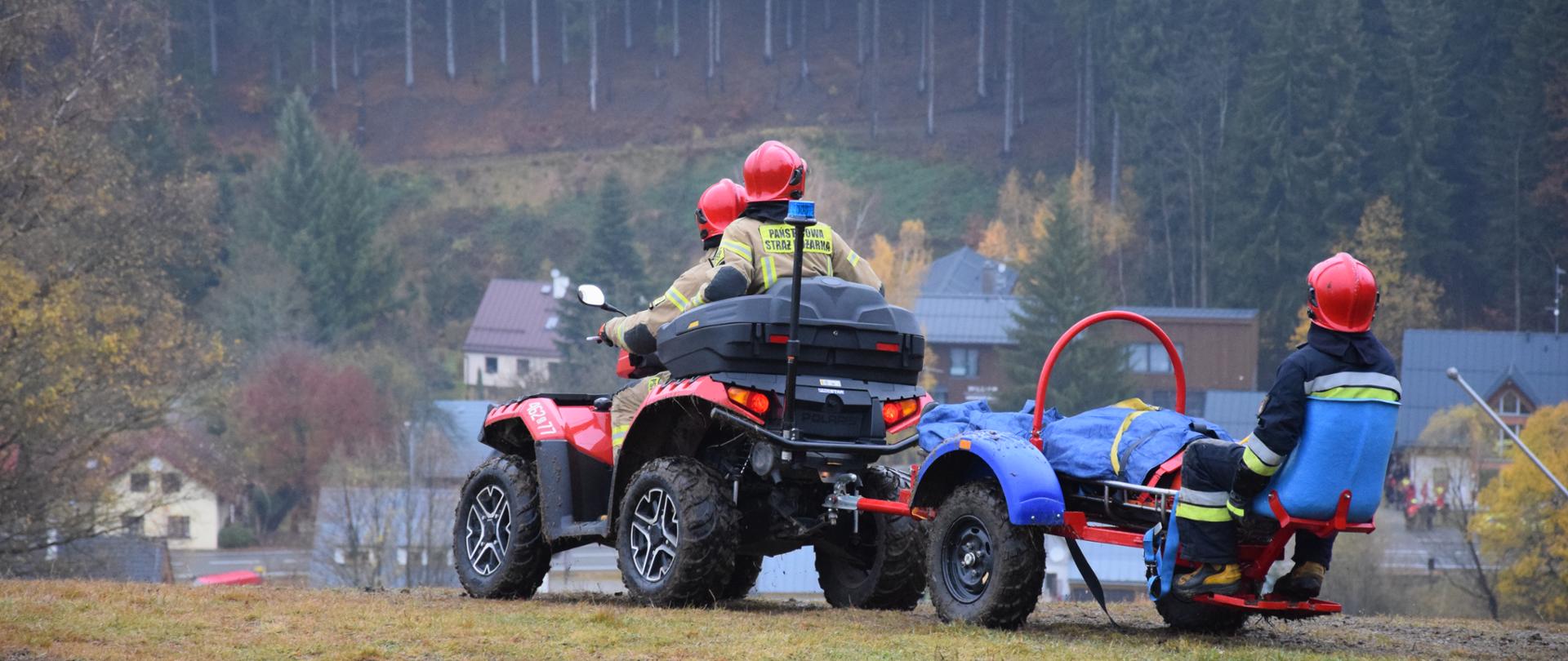 Stok górski. Ratownicy przewożą quadem na przyczepce osobę poszkodowaną.