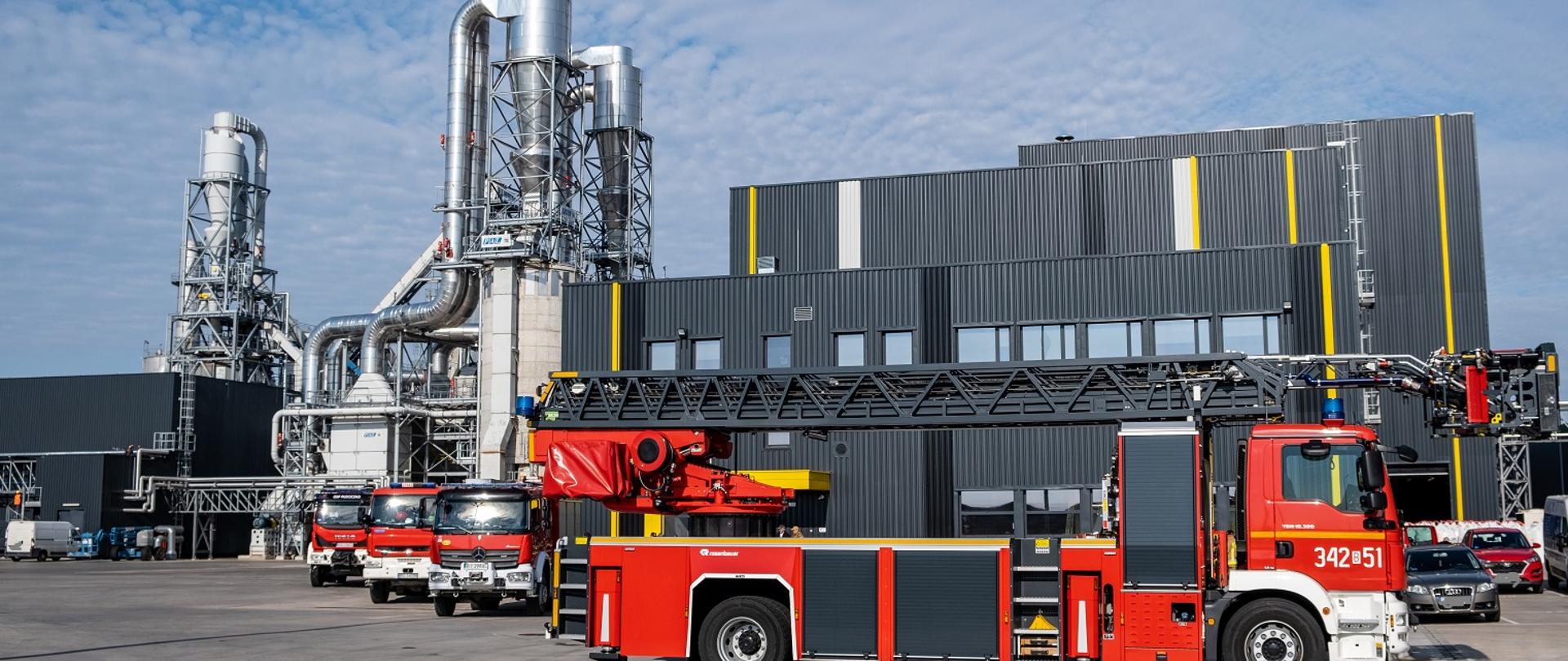 Na zdjęciu widać samochody pożarnicze w tle budynki fabryki