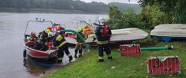 Strażacy na brzegu Wyspy Edwarda wyładowujący sprzęt gaśniczy z łodzi 