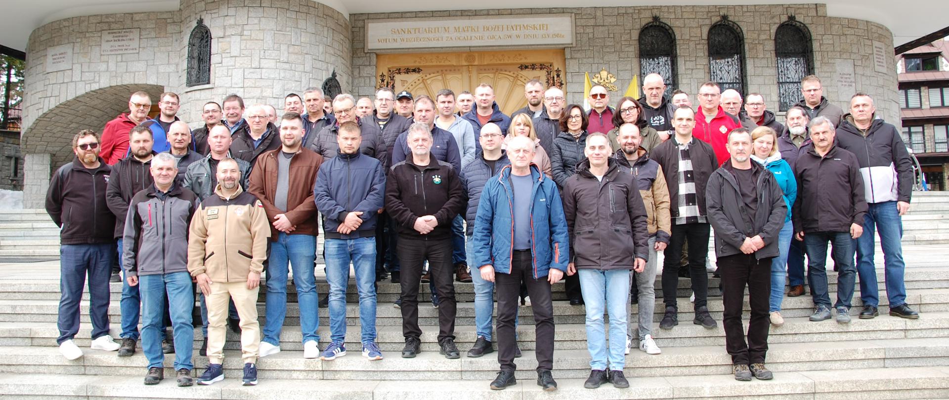 W centralnej części zdjęcia grupa ludzi na tle budynku kościoła.