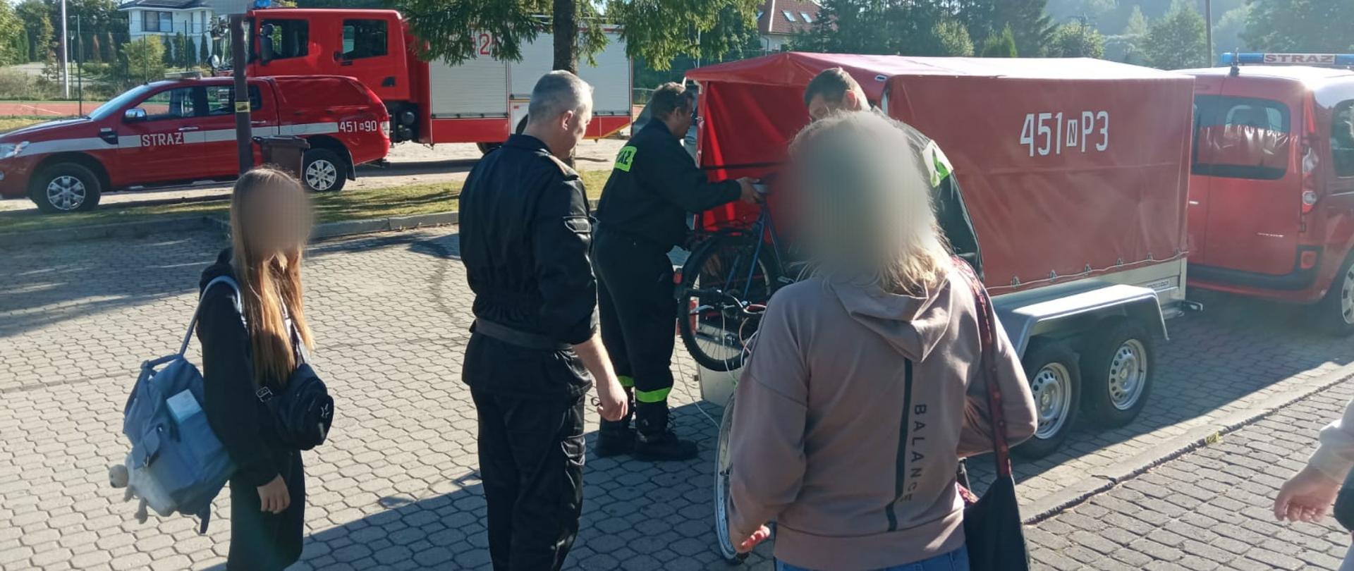Zdjęcie przedstawia strażaków Komendy Powiatowej Państwowej Straży Pożarnej w Gołdapi, którzy udzielają pomocy w transporcie uchodźcom z Ukrainy (w tym pakowanie bagażów) przy użyciu pojazdów pożarniczych