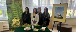 Uczestnicy stoją przy stole promocyjnym Ligi Ochrony Przyrody z materiałami edukacyjnymi i słodyczami