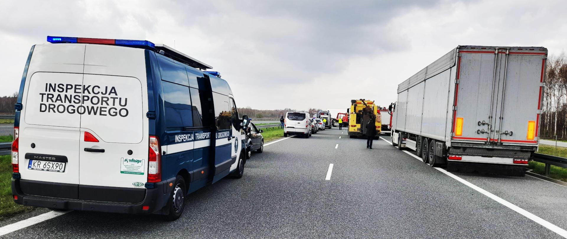 Inspektorzy małopolskiej Inspekcji Transportu Drogowego wsparli służby prowadzące czynności na miejscu wypadku na A4. Na pierwszym planie inspekcyjny furgon, przed nim inne pojazdy służb i miejsce zdarzenia.