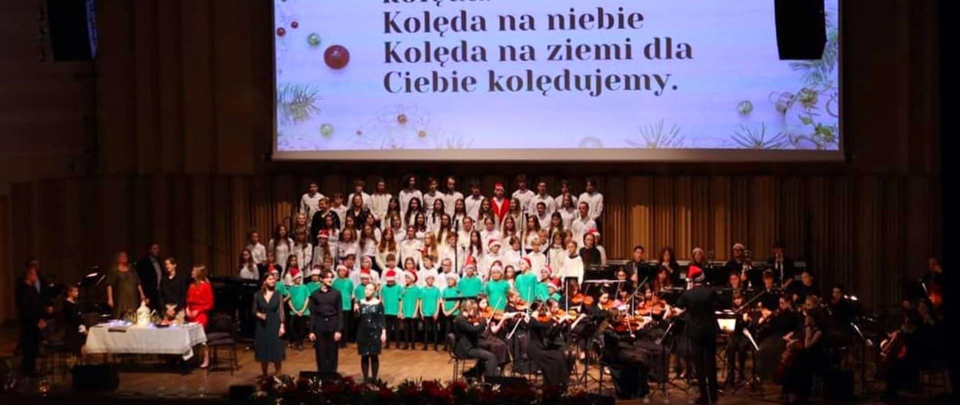 Zdjęcie zbiorowe - chóry, orkiestra, soliści, prowadzący na scenie filharmonii