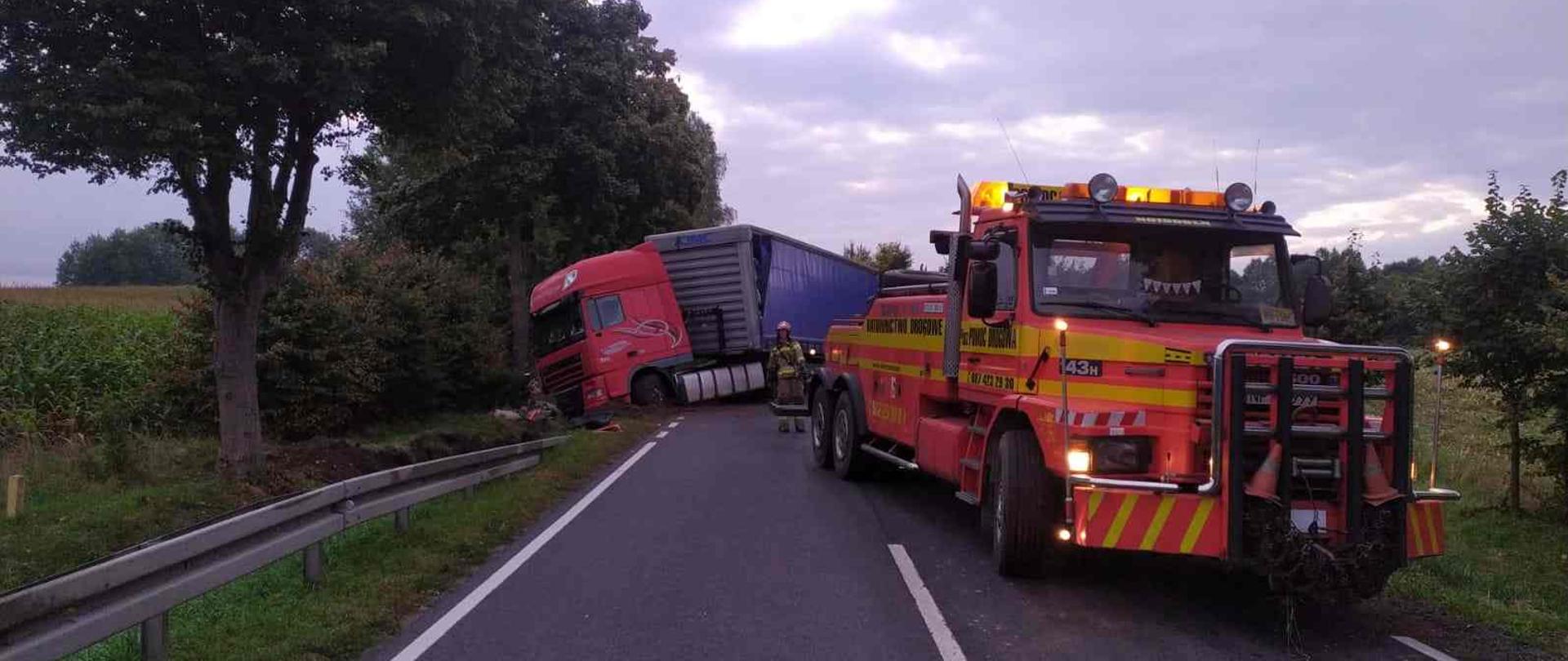 Tir stojący częściowo w rowie wydobywany przez pomoc drogową.