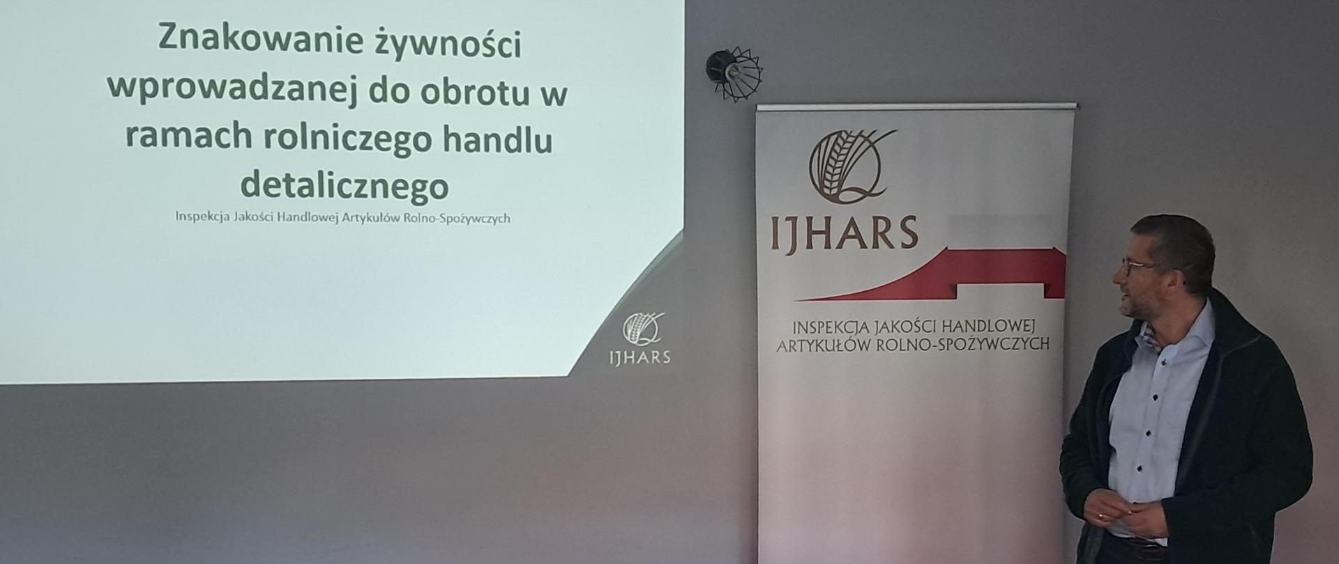 Kierownik Wydziału Kontroli podczas szkolenia. W tle wyświetlana prezentacja.