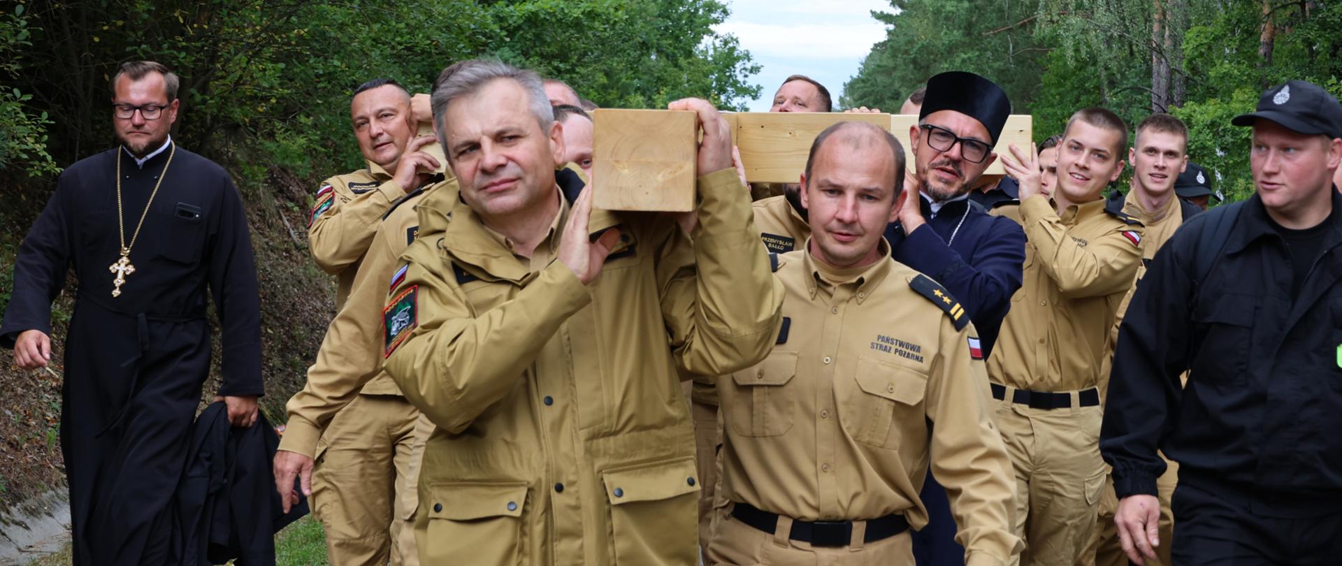 31. Piesza Pielgrzymka Wojska i Służb Mundurowych na Św. Górę Grabarkę - szef podlaskich strażaków niesie krzyż wotywny, za nim funkcjonariusze PSP z regionu
