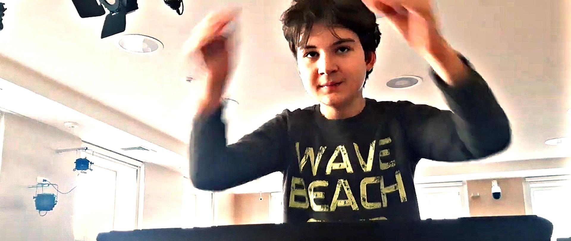 Grafika przedstawia dyrygującego ucznia