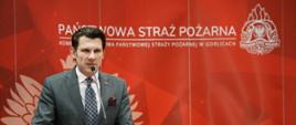 Zajęcie przedstawia przemawiającego komendanta powiatowego Państwowej Straży Pożarnej w Gorlicach podczas narady rocznej podsumowującej działalność Komendy Powiatowej Państwowej Straży Pożarnej w Gorlicach za 2024 rok.