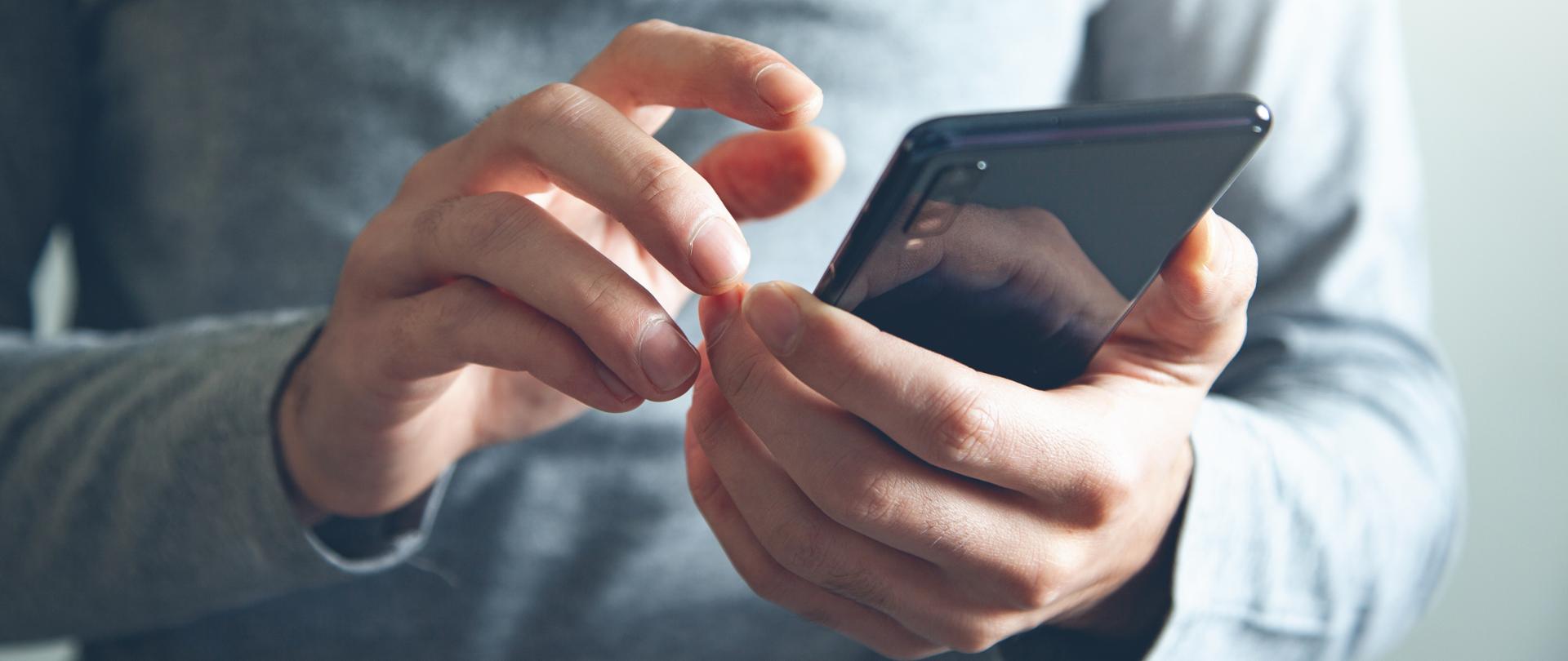 Young farmer with laptop standing in field in front of tractor with smart sowing equipment